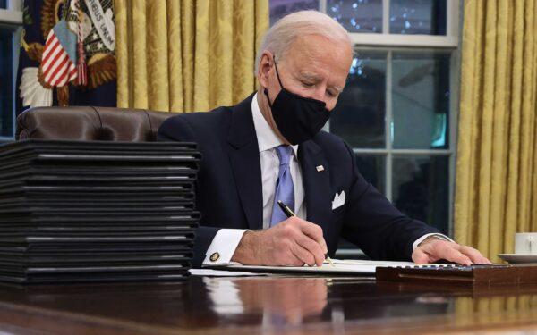 President Joe Biden signs a series of executive orders at the Resolute Desk in the Oval Office just hours after his inauguration in Washington, on Jan. 20, 2021. (Chip Somodevilla/Getty Images)