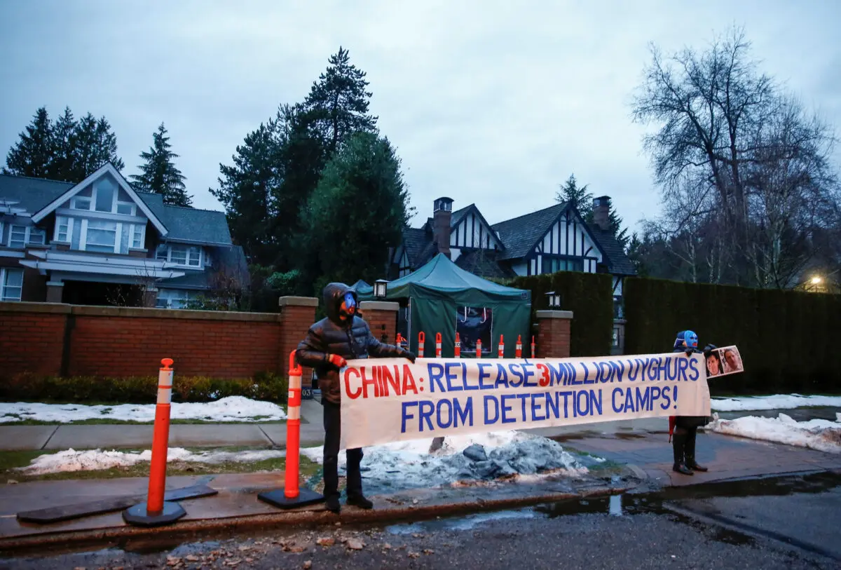 Protesters hold a sign against China's Uyghur camps, labeled vocational training centers by the Chinese regime, outside the home of Huawei CFO Meng Wanzhou before her extradition hearing at B.C. Supreme Court in Vancouver, British Columbia, Canada, on Jan. 20, 2020. (Lindsey Wasson/Reuters)