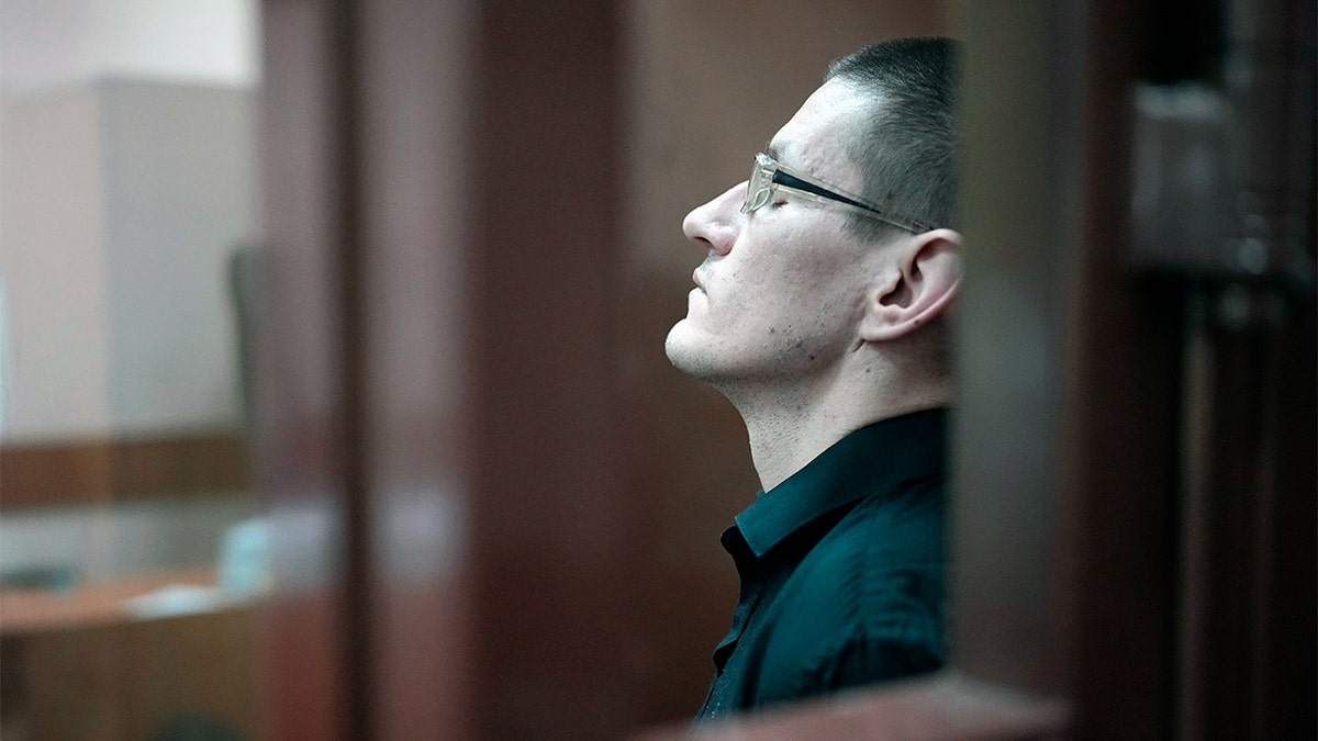 Robert Woodland sitting in glass cage in Russian court