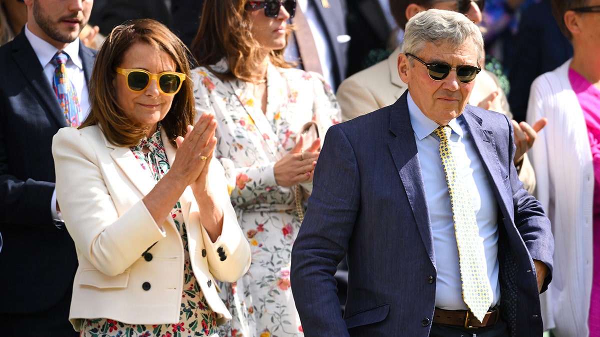 Carole Middleton claps and wears yellow sunglasses next to husband Michael Middleton in a blue suit and yellow tie at Wimbledon