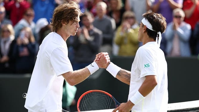 Argentina's Francisco Comesana (R) shakes hands after winning against Russia's Andrey Rublev during their men's singles tennis match on the second day of the 2024 Wimbledon Championships.