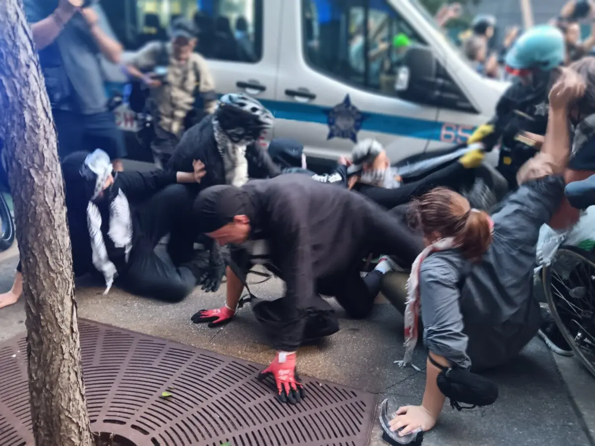 A protester is toppled as police and demonstrators clash near the Israeli consulate in Chicago on Aug. 20, 2024, against the backdrop of the Democratic National Convention (Nathan Worcester/The Epoch Times).