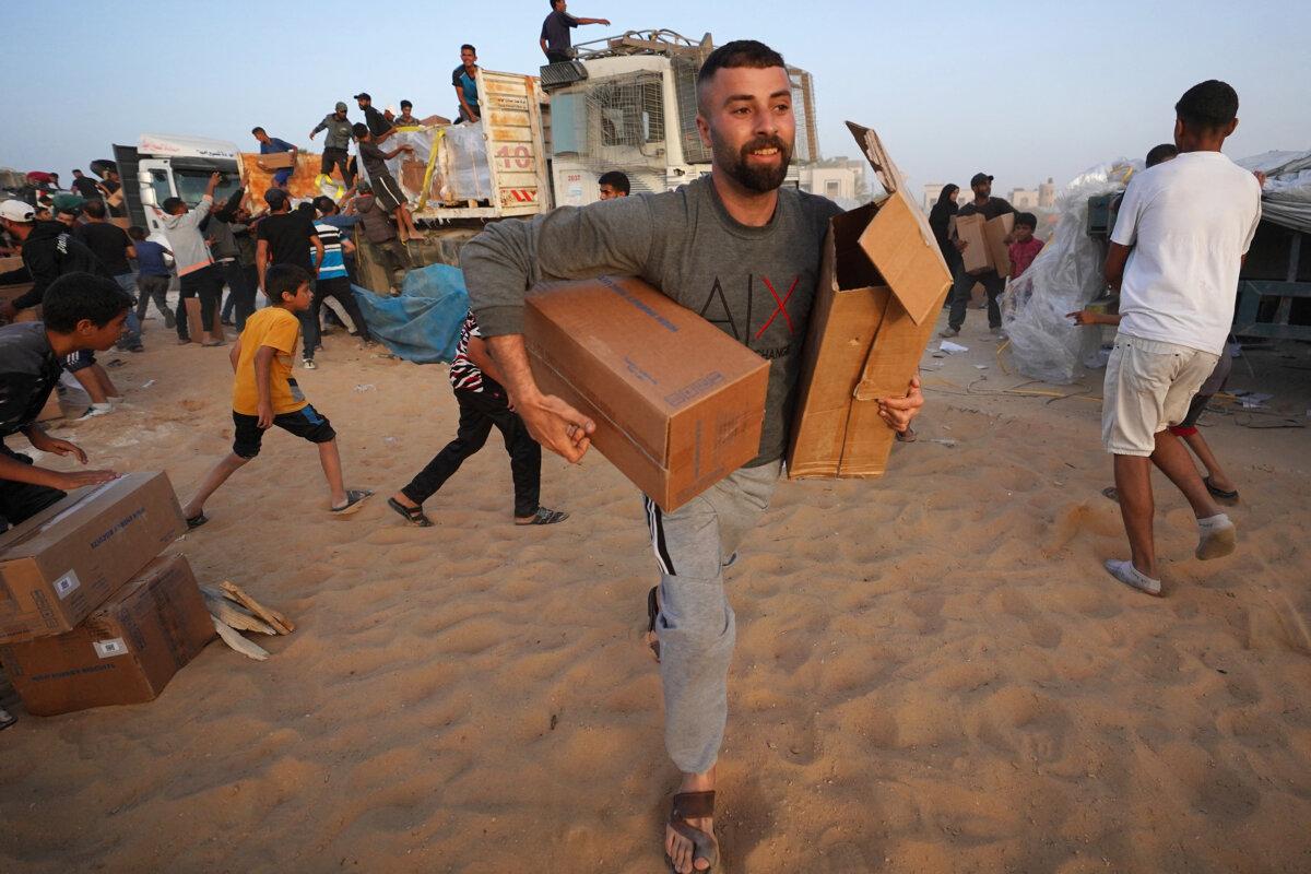 Palestinians carry boxes of humanitarian aid after rushing trucks from the U.S.-built Trident Pier near Nuseirat in the central Gaza Strip on May 18, 2024. (AFP via Getty Images)