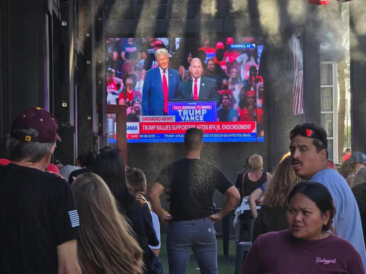 Trump supporters watch the former president on a wide television during a rally in Glendale, Ariz., on Aug. 23, 2024. (Allan Stein/The Epoch Times)