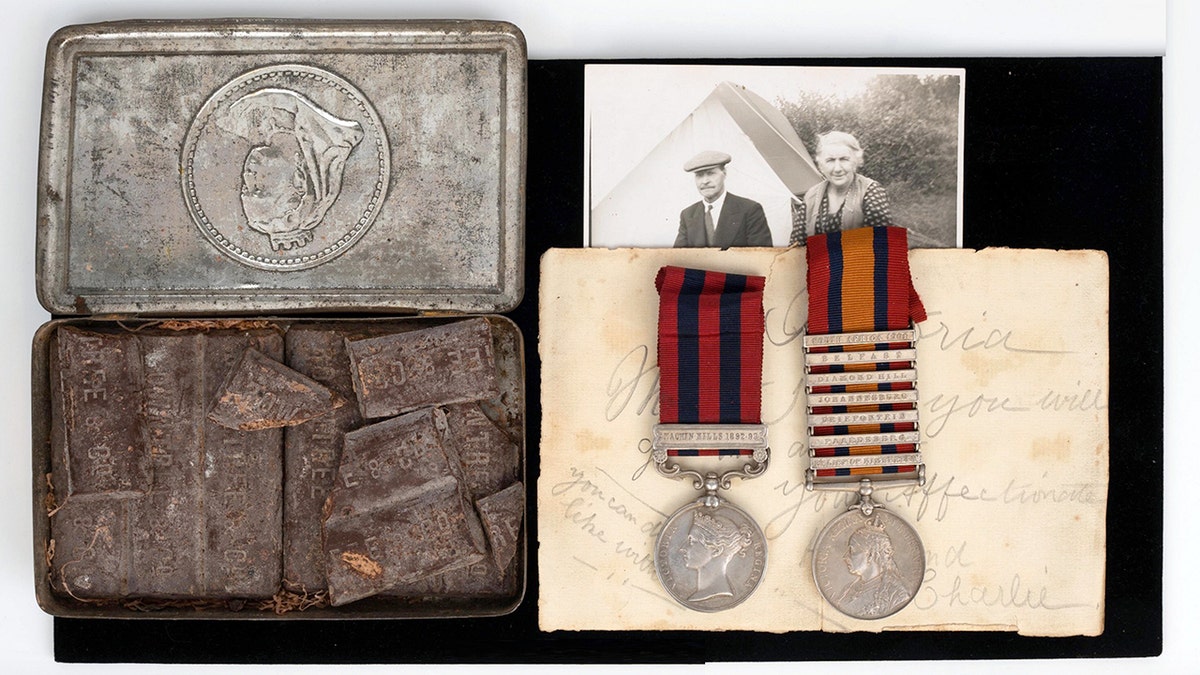 An auction lot featuring medals, a letter, and a very old box of chocolate. 