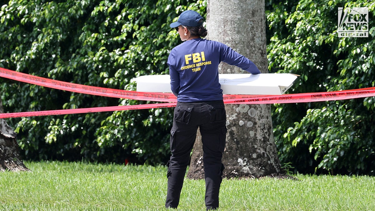 FBI investigators carry a box of evidence from the perimeter of Trump International Golf Club in West Palm Beach