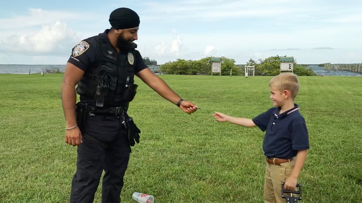 An officer hands a child a reward coin