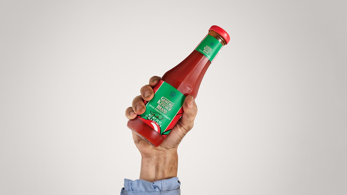 A bottle of ketchup held by a hand.