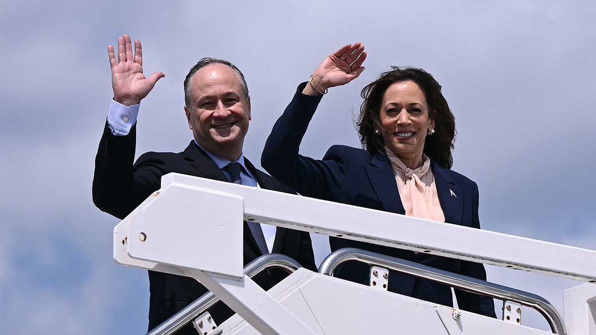 US Vice President and 2024 Democratic presidential candidate Kamala Harris and Second Gentleman Doug Emhoff wave as they board Air Force Two