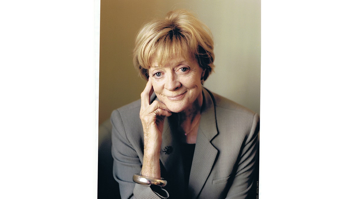 Maggie Smith smiles with her hand by her face