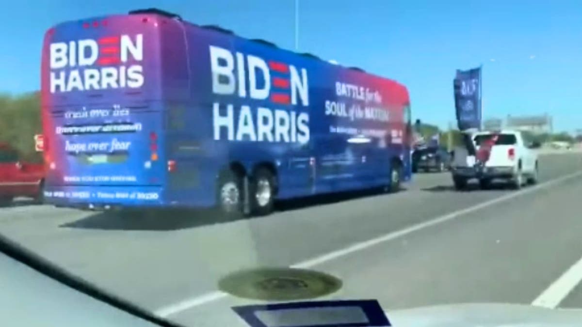 A pick-up truck with Trump flags flanks a Biden-Harris campaign bus