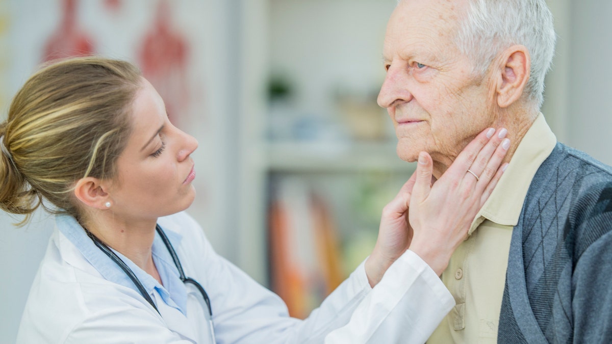 Doctor checking older mans thyroid gland