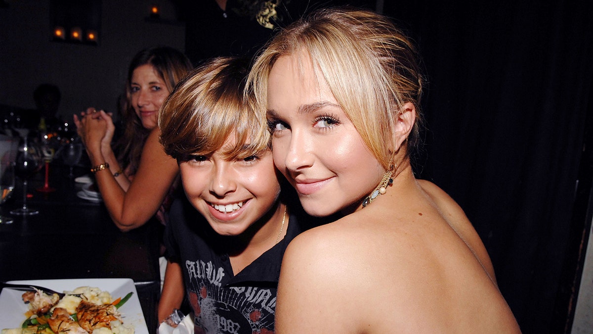 A young Jansen Panetierre smiles wide with big sister Hayden Panetierre who soff smiles with her back partially to the camera