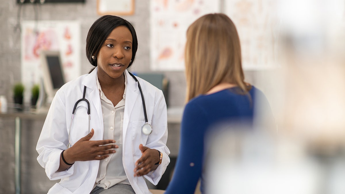 A female doctor sits across from her female patient