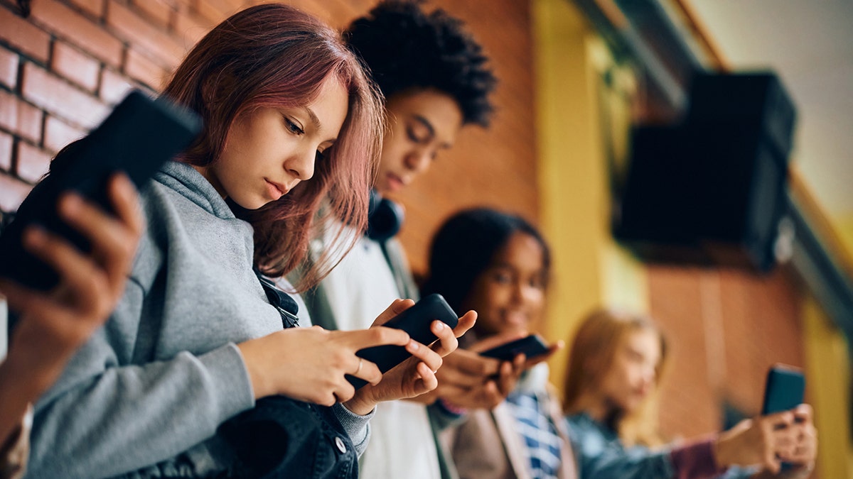 High school students using their smart phones in a hallway