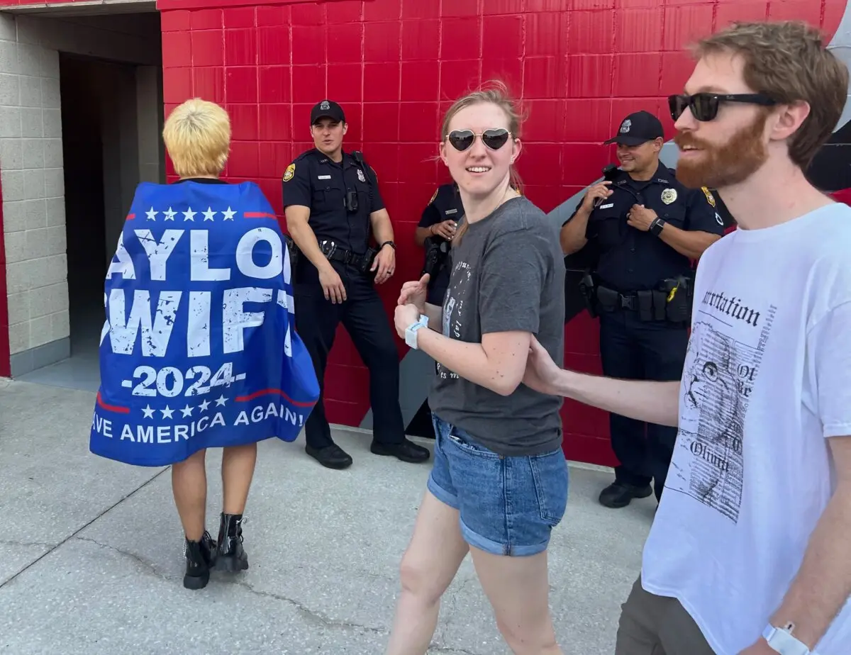 A fan wrapped in a flag that says Taylor Swift 2024 Save America Again waits in a stadium ahead of the star's The Eras Tour concert in Tampa, Fla., on April 15, 2023. (Natasha Holt/The Epoch Times)