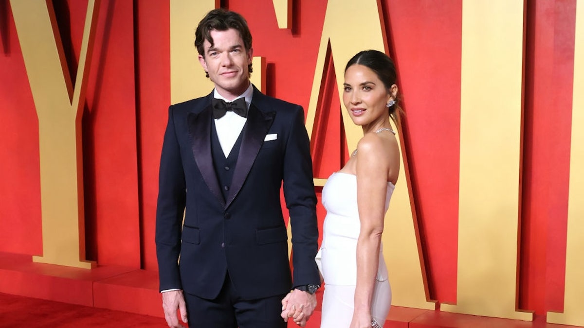 Olivia Munn walks red carpet wearing white dress with her partner, John Mulaney.