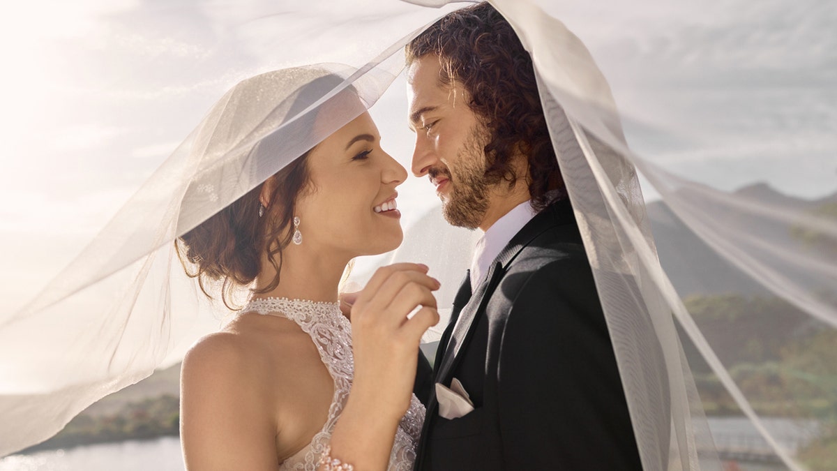 A bride and groom underneath her wedding veil 