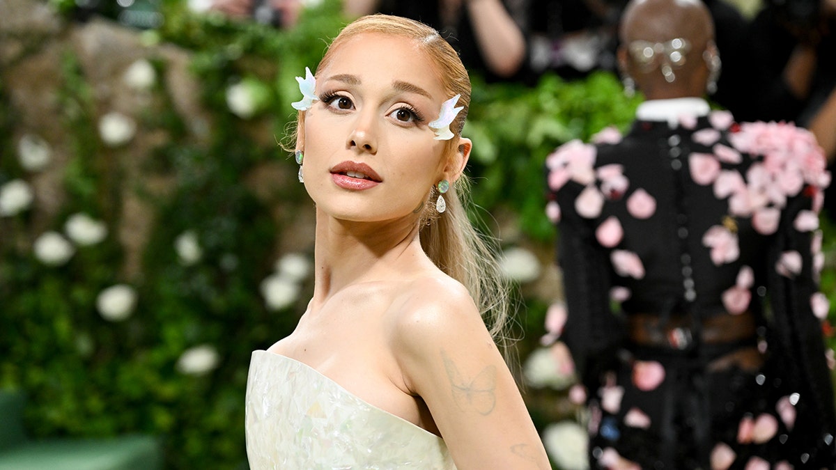 Ariana Grande in a strapless gown looks up and away on the carpet at the MET GALA