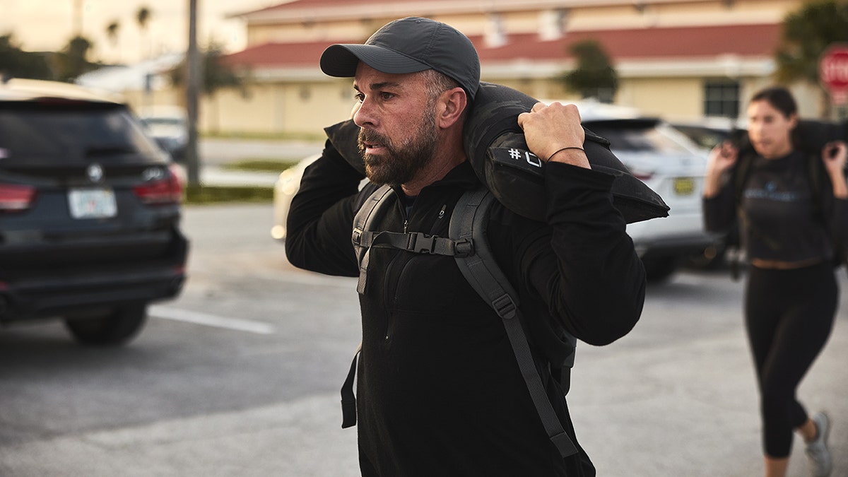 man carrying sandbag weight