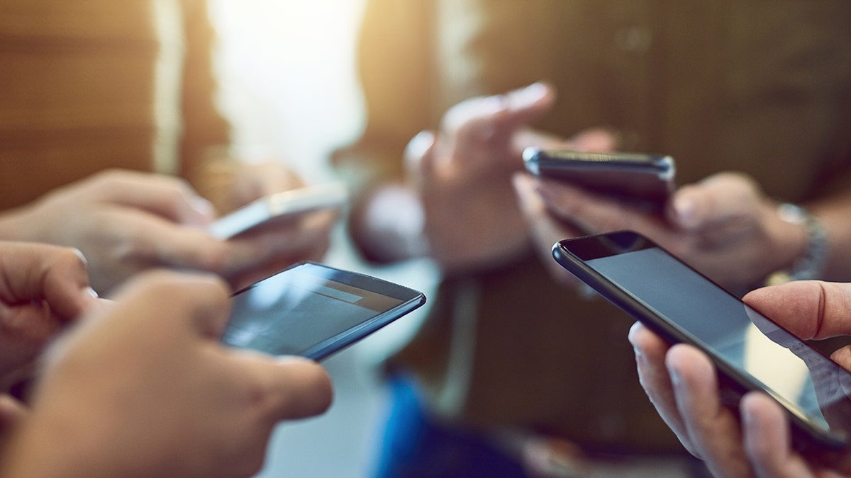 Cropped shot of a group of colleagues using their smart phones in synchronicity