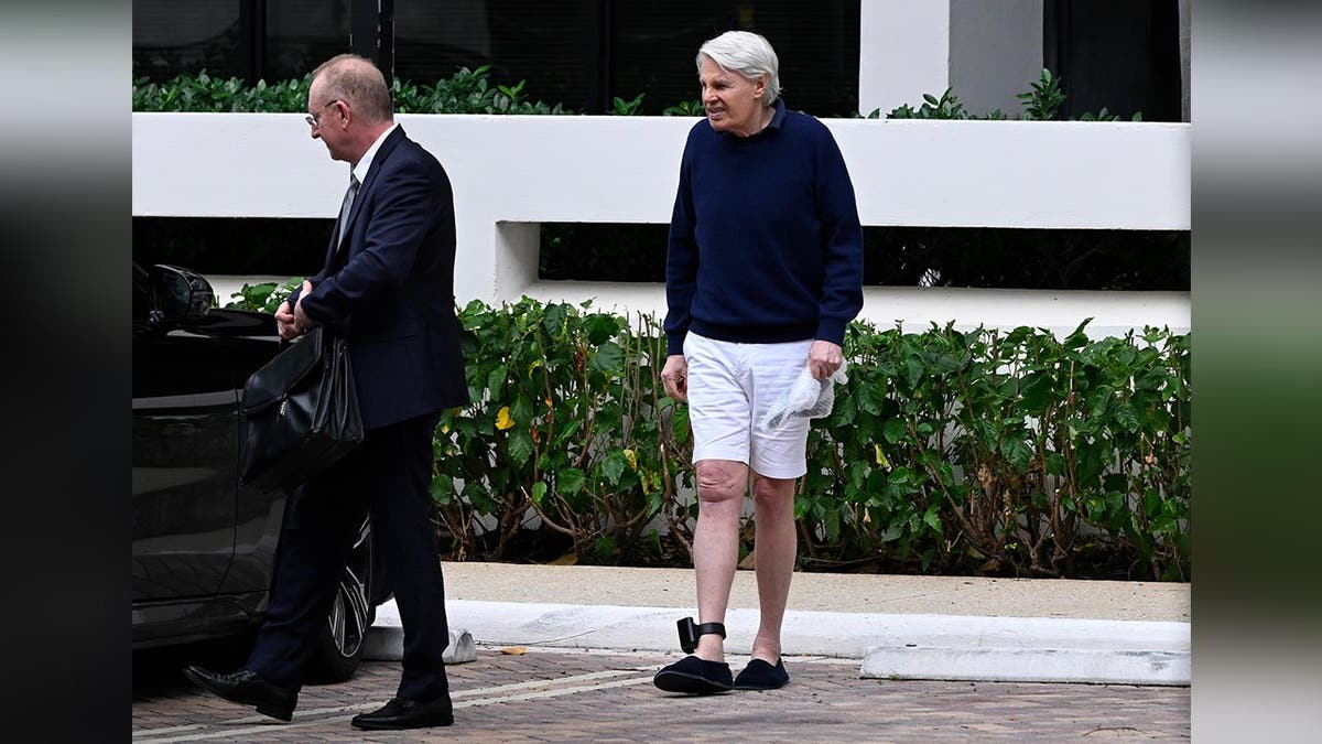 An ankle monitor fitted to the leg of former Abercrombie and Fitch CEO Mike Jeffries is visible as he walks away from an office building.