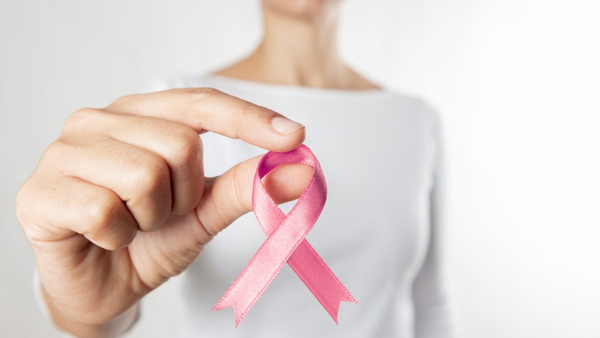 A woman holding a breast cancer ribbon