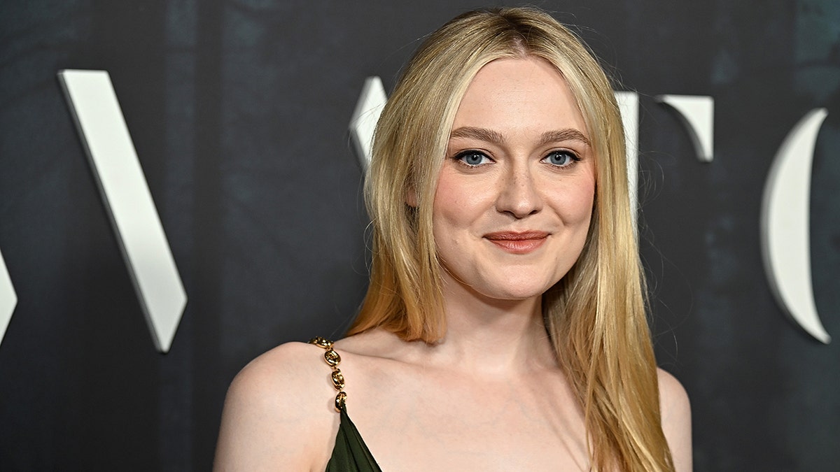 Dakota Fanning soft smiles on the carpet in a green dress