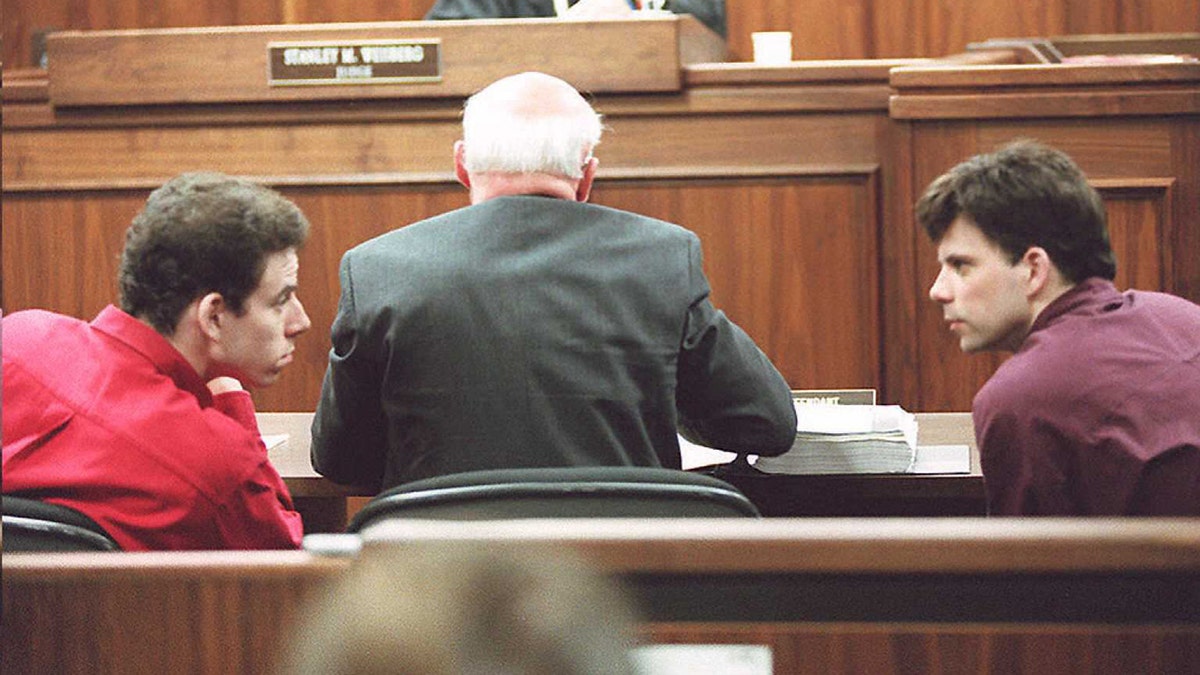 Erik and Lyle Menendez lean back to say something to the other in court behind their attorney