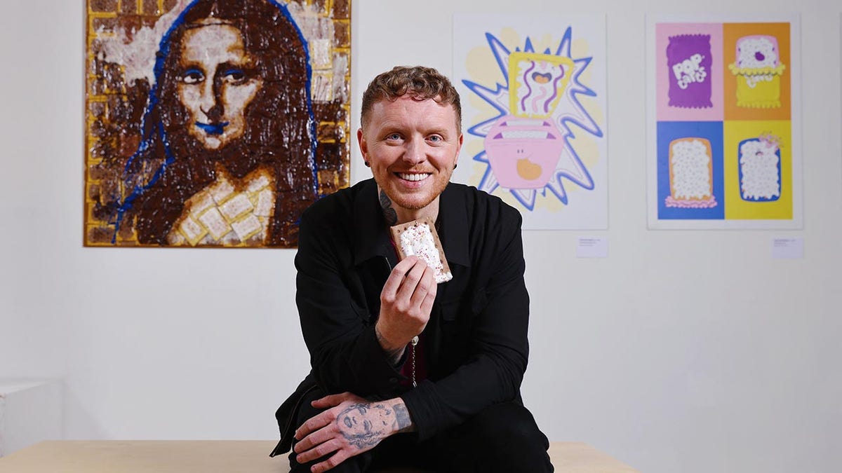 Man holding a pop tart in front of a portrait of the Mona Lisa made from pop tarts.