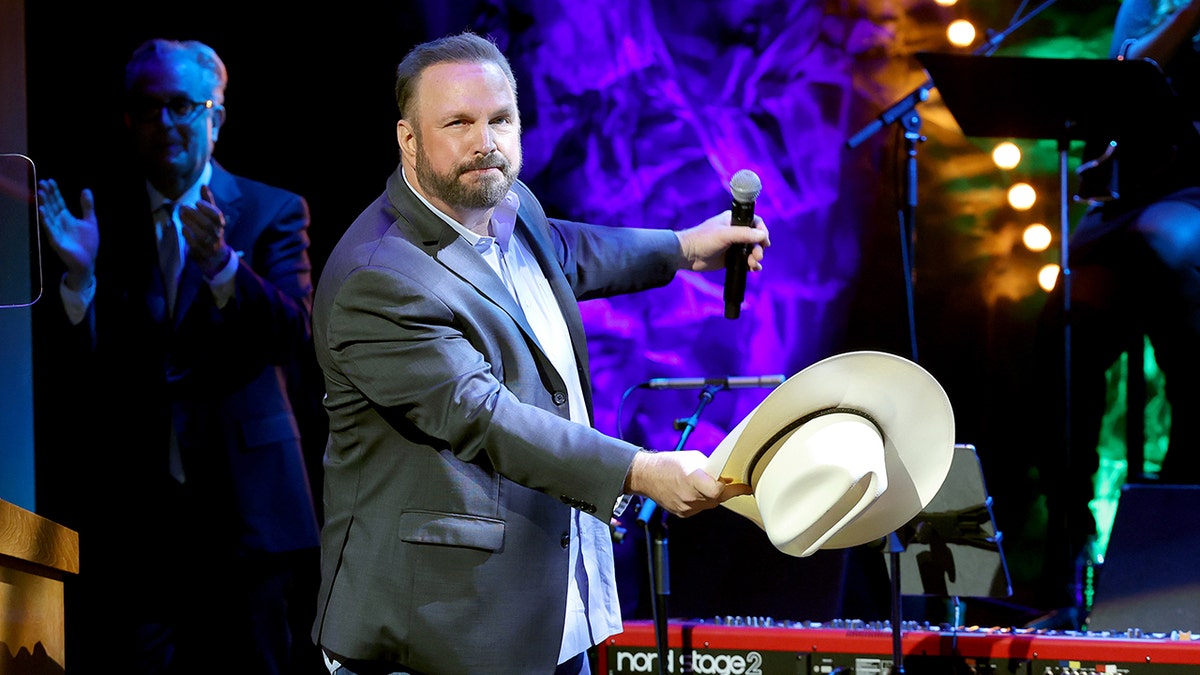 Garth Brooks hangs his cowboy hat low as if he had just taken it off while on stage