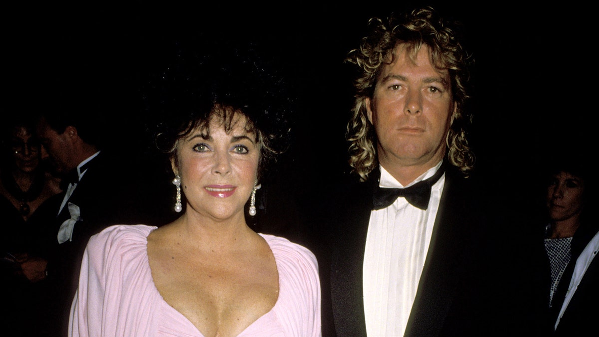 A close-up of Elizabeth Taylor in a pink dress with her last husband in a tux.