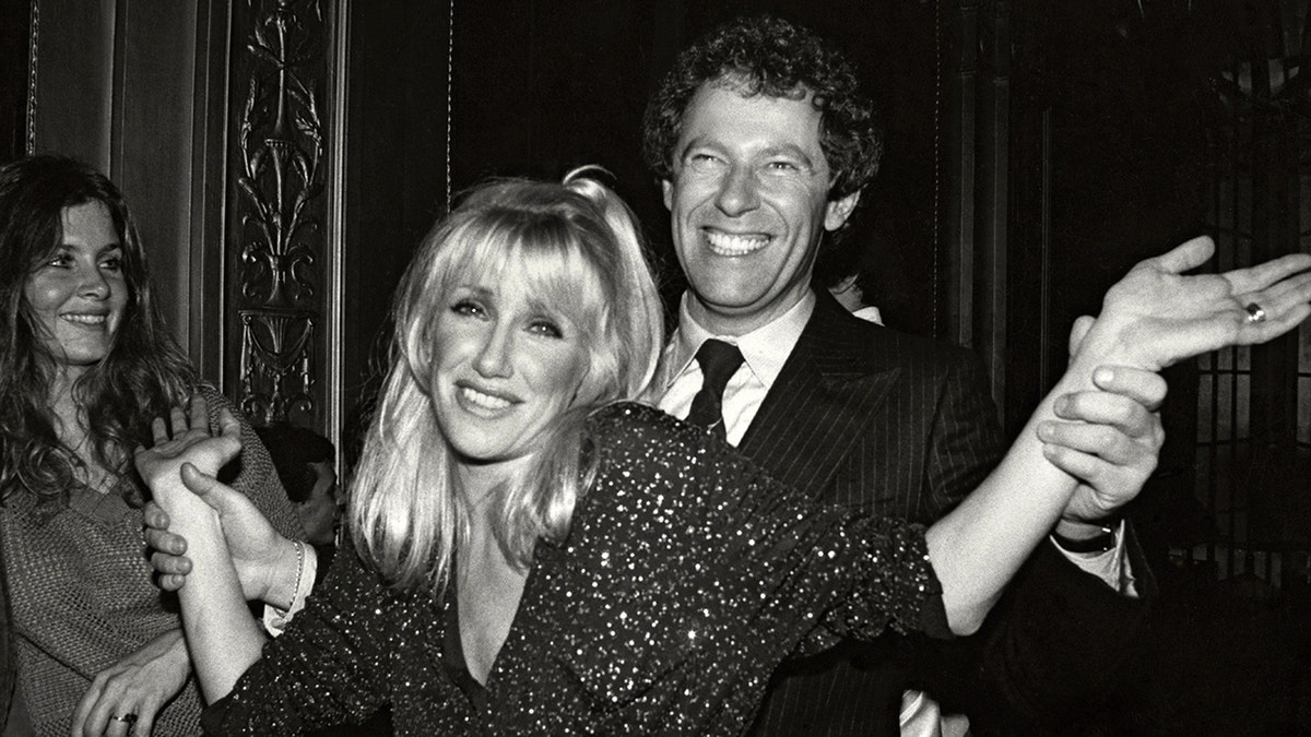 Alan Hamel smiling as he holds on to Suzanne Somers hands