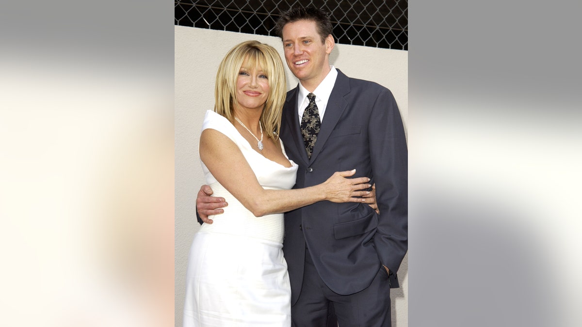 Suzanne Somers in a white dress embracing her son Bruce