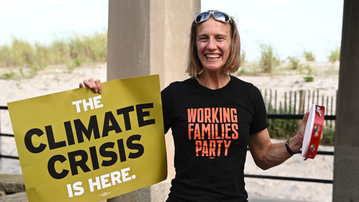 Altman holds climate crisis sign wearing Working Families Party shirt