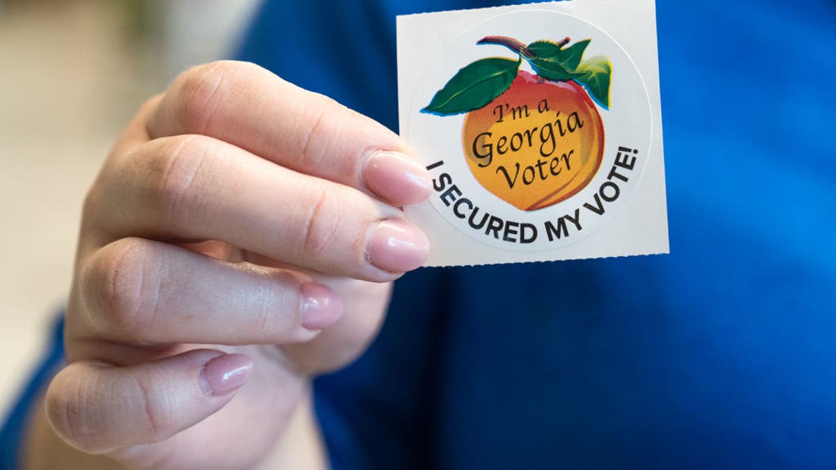 A voter holds up her sticker after casting her ballot for the primary election on March 12, 2024, in Atlanta, Georgia.