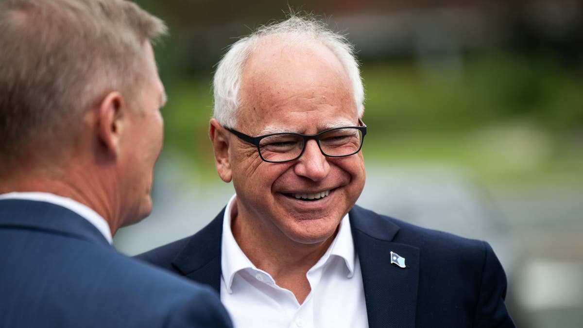 Tim Walz, man with white hair, smiling with black rimmed glasses