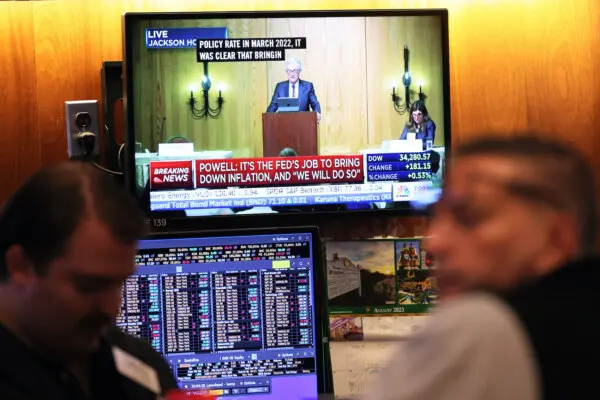 Federal Reserve Chairman Jerome Powell’s speech is seen on a television screen as traders work on the New York Stock Exchange floor during morning trading on Aug. 25, 2023. (Michael M. Santiago/Getty Images)