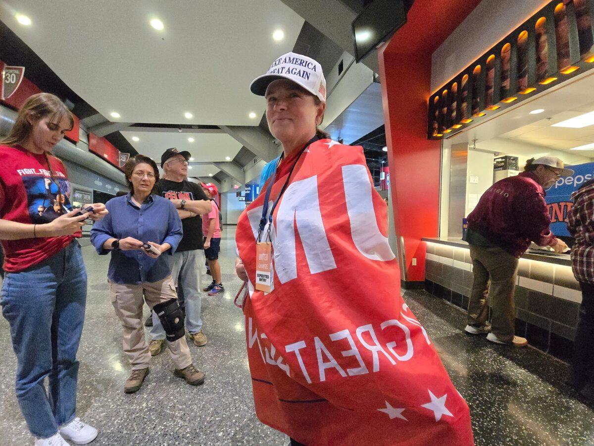 Gina Calabrase drapes herself in a banner supporting former President Donald Trump during a rally in Las Vegas on Oct. 24, 2024. (Allan Stein/The Epoch Times)