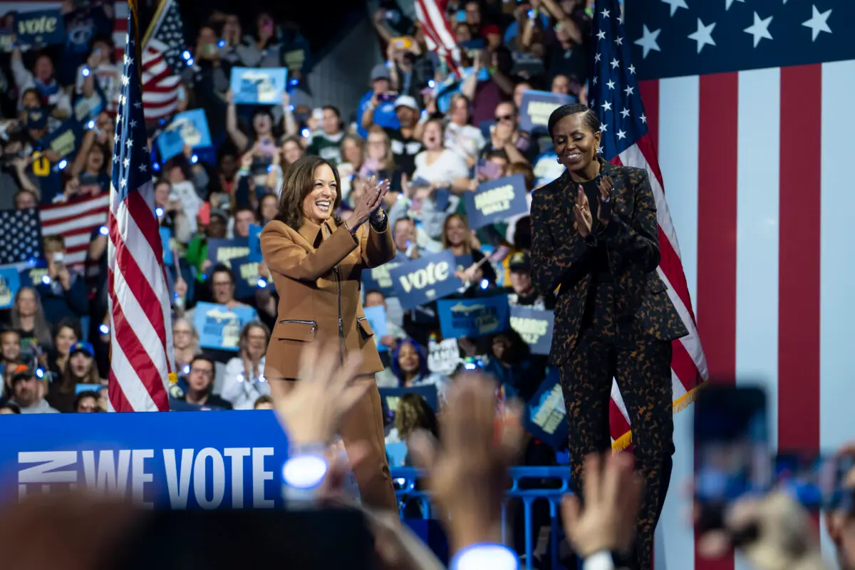 Democrat presidential candidate Vice President Kamala Harris and former First Lady Michelle Obama greet on stage during an event at Wings Event Center in Kalamazoo, Mich., on Oct. 26, 2024. (Madalina Vasiliu/The Epoch Times)