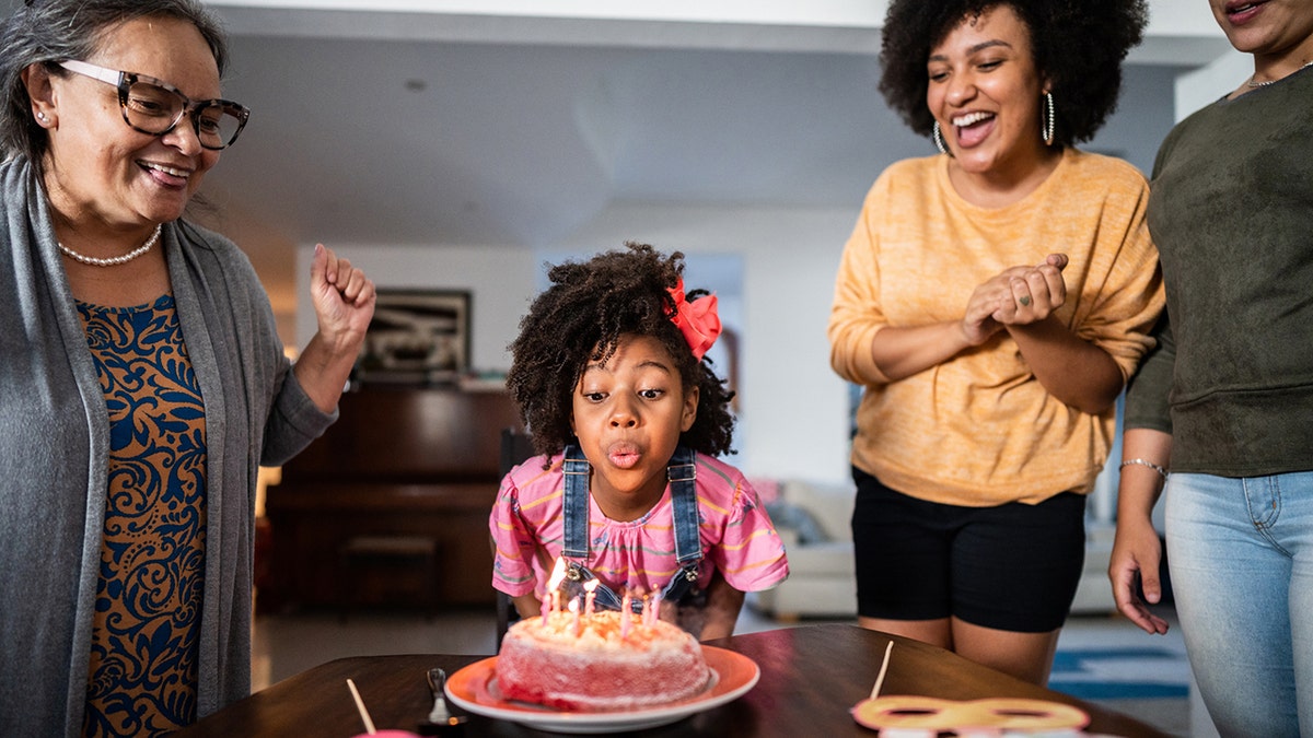 Girl blowing out the candles on her birthday cake