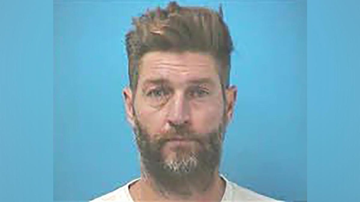 Jay Cutler with a scruffy beard does not smile for his mugshot