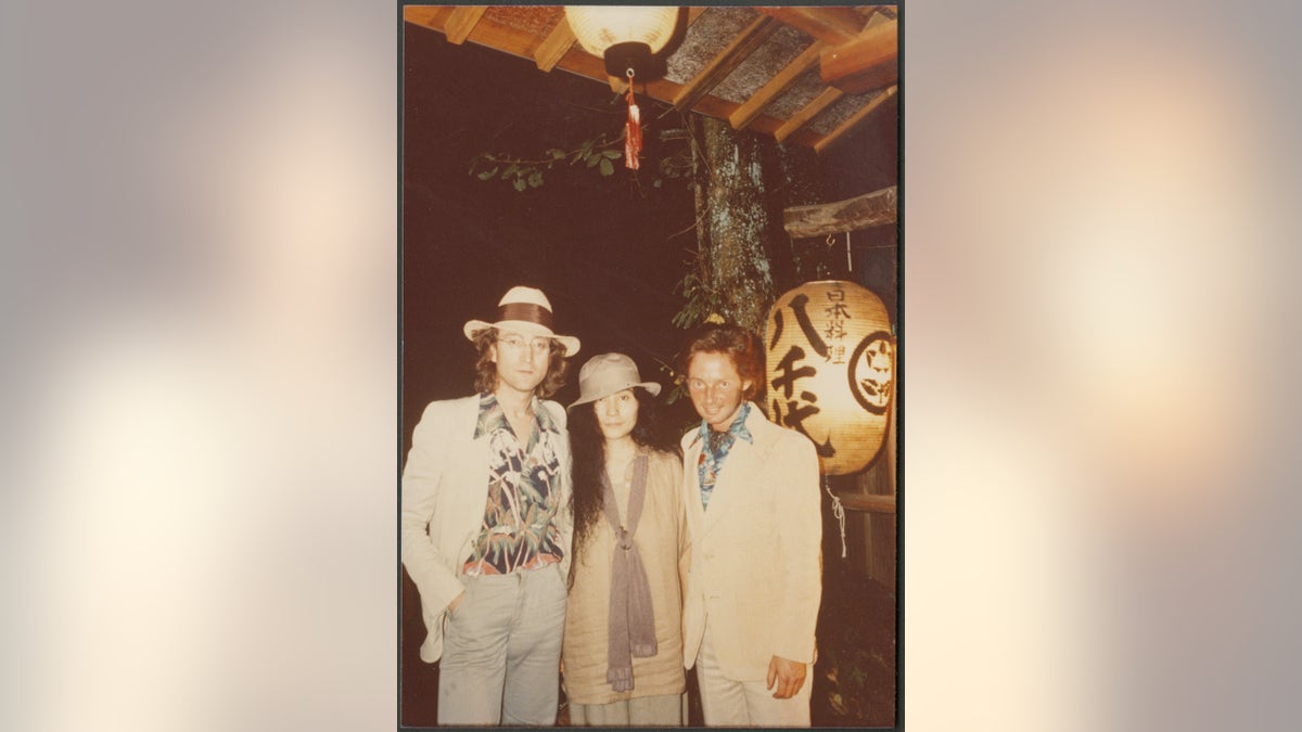 John Lennon, Yoko Ono and Elliot Mintz standing together near a Japanese lantern