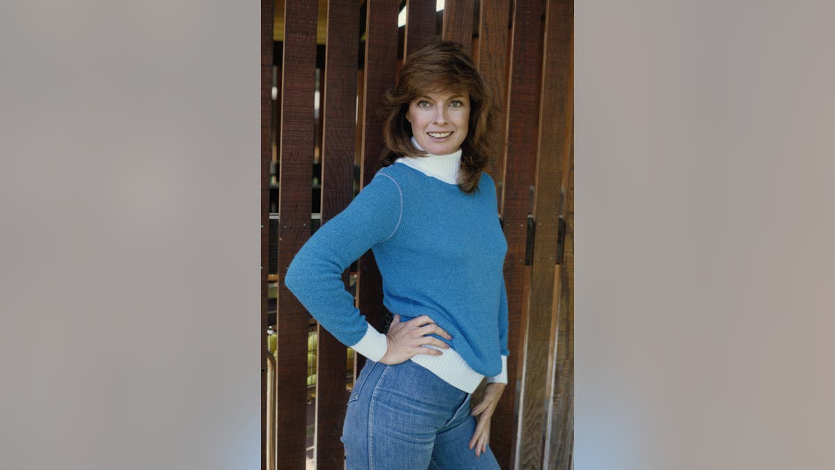 Linda Gray posing near a fence in the 1980s