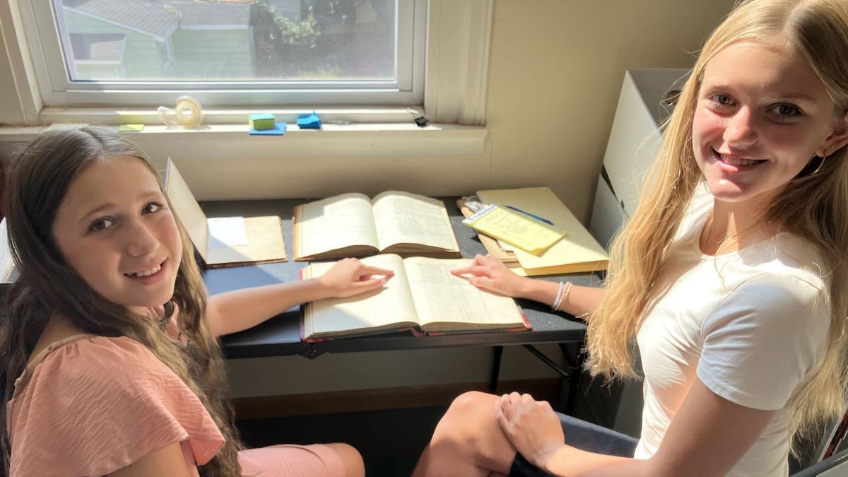 Girls smiling holding old document