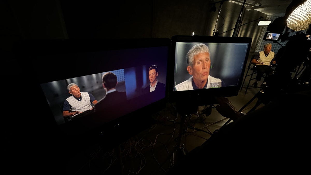 Monitors show Matt Finn sitting across from Rick Singer.