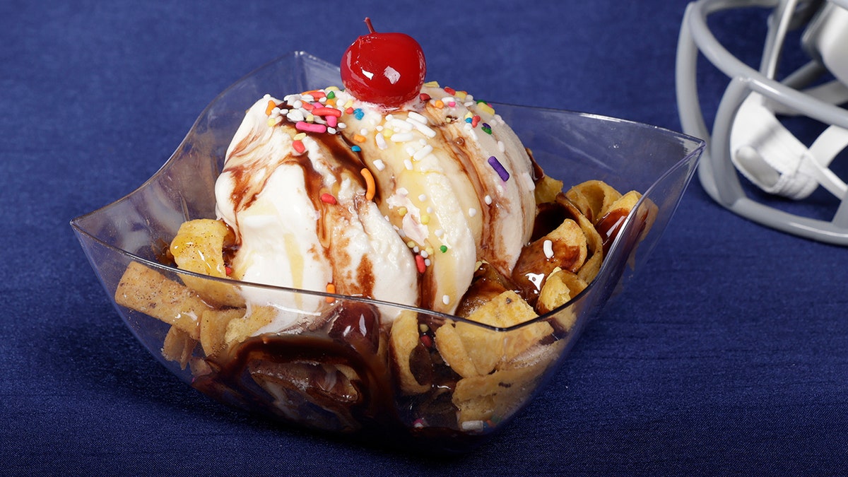 A sundae made out of vanilla ice cream and topped with fritos and hot fudge.