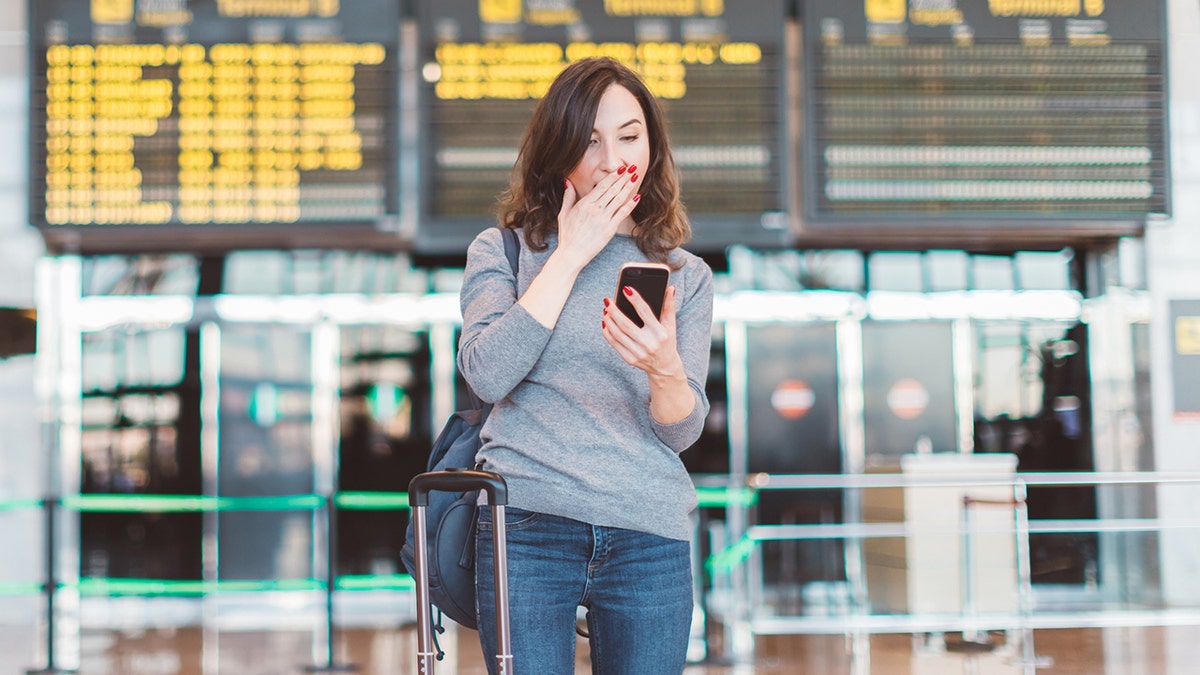 woman looks at phone in shock