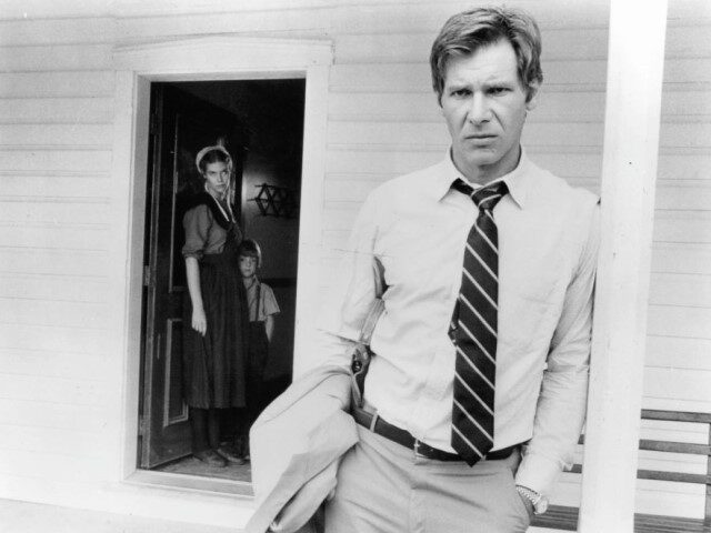 Kelly McGillis, Lukas Haas, and Harrison Ford stand by a white house in a scene from the f