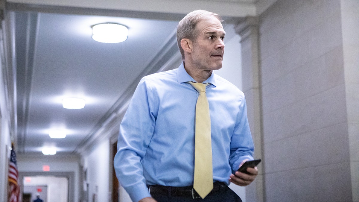 Jim Jordan holding phone in hallway